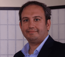 A man in a suit and tie standing next to a wall.