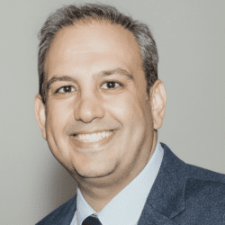 A man in a suit and tie standing next to a wall.